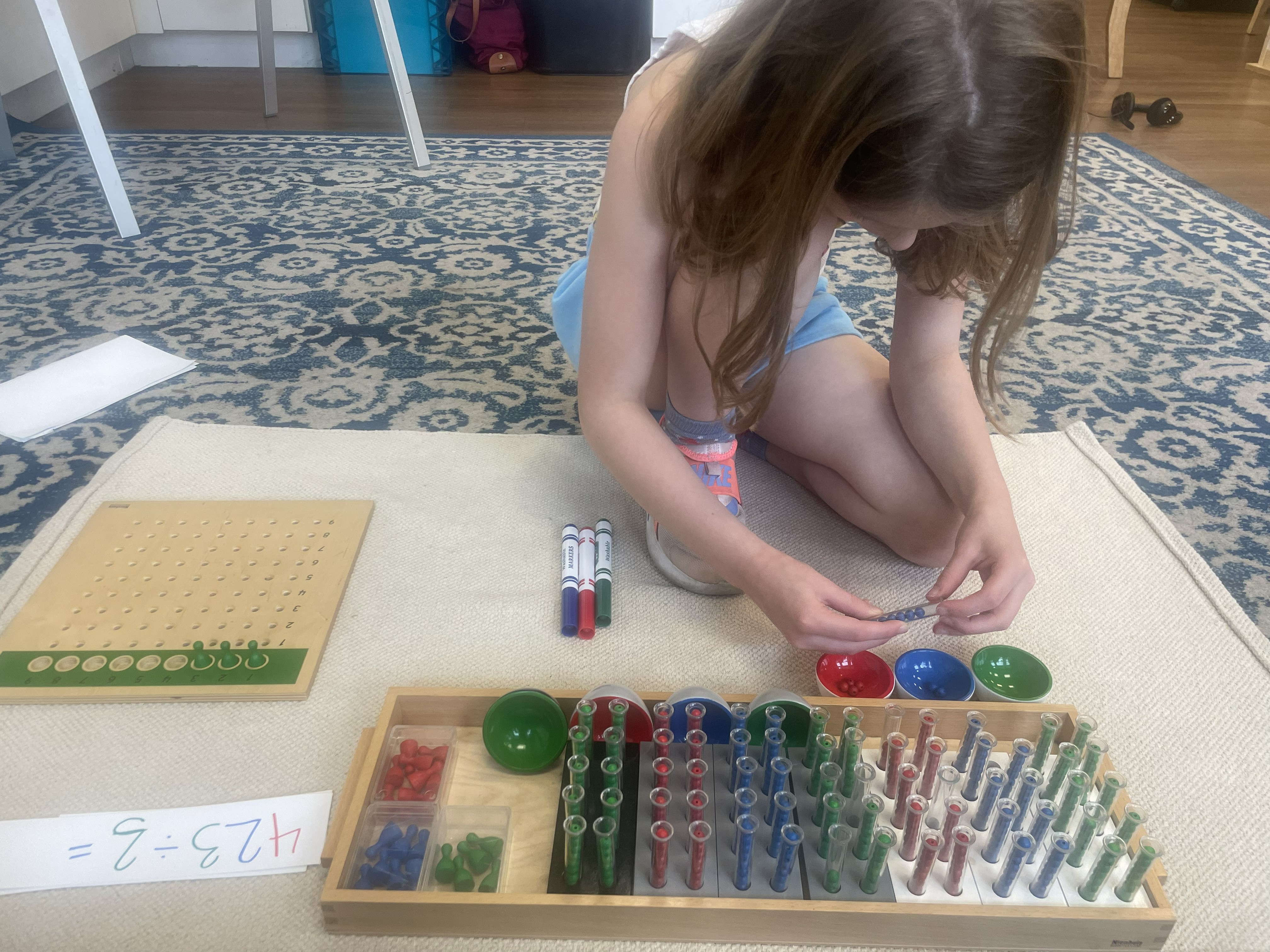 Student working with Montessori division material and test tubes